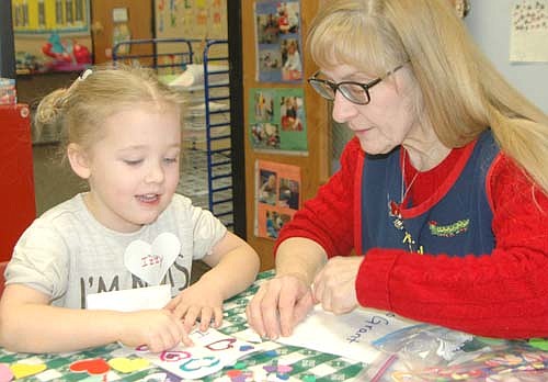 Kathy Dux, a butterfly teacher at the St. John's Wee Care Learning Center, works with Izzy Slovinski, 5, of Stewartville, on a Valentine's Day project on Thursday morning, Feb. 13.