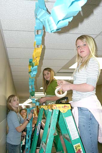 LINKED BY KINDNESS -- Accepting Rachel Scott's challenge to be kind and compassionate, students at Stewartville Middle School began decorating the school's halls with paper rings last week.  Each ring represents one student's act of kindness toward another.  Brittanie Hoerner,  a sixth-grader on the ladder in the foreground, and Malia Parker,  a seventh-grader on the ladder in the background, worked on the project last week. Craig Bell, school guidance counselor, said the school's goal is to link the rings throughout the entire school. Rachel Scott's family and friends started  "Rachel's Challenge," an initiative to promote kindness, after Rachel was killed in the shootings at Columbine High School.  Rachel had lived a life of kindness and compassion toward others. 
