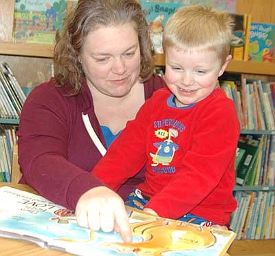 A large group of students and parents attended the annual St. John's Wee Care Pajama Party on Tuesday evening, March 5. Here, Erin Plizga of rural Stewartville reads The Cow Loves Cookies to her son Owen, 4, a Wee Care student.