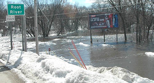 Snow that had fallen in huge quantities on Stewartville's neighborhoods and parks, including the 12 inches that fell during a windblown winter storm on Feb. 23 and 24, started to melt in mid-March. On Friday, March 15, the melting snow and huge chunks of ice clogged the Root River, above, rising to within about two feet of the walking bridge near Meadow Park. Also on March 15, water from the Root River, spills over its banks just west of the Main Street bridge.