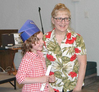 Roran Smith, left, received his diploma at the Wee Care Learning Center's annual graduation ceremony at St. John's Lutheran Church on Sunday, May 5. Kathy Dux, Wee Care butterfly teacher, congratulates Roran. Seventeen children took part in the ceremony.