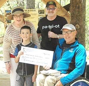 Lance and Renee Garrick of Red Wing, standing in back and accompanied by a young family friend in front at left, present a $2,000 check to Bob Bardwell, founder of Ironwood Springs Christian Ranch, as part of the Military Tribute at Ironwood's new Chuckwagon facility during the Ranch's Memorial Bash on Saturday afternoon, May 25. Ironwood Springs Christian Ranch will use the money to help pay for its many Operation Welcome Home activities for America's veterans, Bardwell said. The Garricks presented the check on behalf of Hiawatha Valley Family Beyond the Yellow Ribbon.