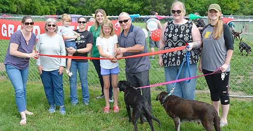 Mayor Jimmie-John King, third from right, and members of the Friends of the Dog Park gathered to cut the ribbon to officially open the city's new dog park on Saturday, June 15. Friends of the Dog Park members include, from left, Julie Ristau, Wendy Timm, Katie Johnson (holding Aubrie, Julie Ristau's daugther), Angela Meyer, Amelia Petersen (helping the mayor cut the ribbon), Maren Schroeder and Christie Petersen.