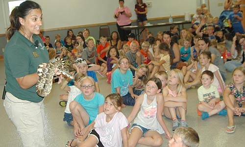 Alex Tasa, a naturalist from the Minnesota Zoo, displays a bull snake to a large audience of children at the Stewartville Civic Center on Wednesday afternoon, June 26. "It's the largest type of snake in Minnesota," Tasa told her listeners. "The record for a bull snake is eight feet long."&#8200;Tasa also brought a skink, a skunk and a tarantula to the event, sponsored by the Stewartville Public Library and the Minnesota Arts and Cultural Heritage Fund.