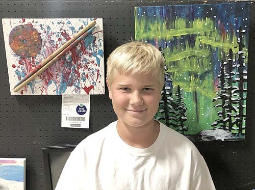 Conner Lohmann poses with his blue-ribbon paintings.