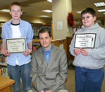 Cody Manning, left, holds the award he won for writing a Father of the Year essay about his dad, Mark Manning, seated. Sam Edge, right, won a similar award for the essay he wrote about his dad, Roy Edge. 