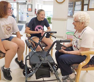 Abbi Parry, left, who will be a freshman at Stewartville High School, and Bryttin Henderson, an incoming SHS&#8200;sophomore, members of the Stewartville YES (Youth Embracing Stewartville) group  who visited the Stewartville Care Center last week, smile brightly as they talk with Evelyn Galligos, 95, a Care Center resident, on Tuesday morning, July 30. Jim Parry, the REACH teacher and YES&#8200;group coordinator at Stewartville High School and Middle School, said visiting the Care Center helps the students grow as people. "The most valuable thing we can share with others is our time," Parry said.