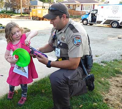 Arianna McCrossen, 4, of Stewartville, pulls a pencil from a stack of pencils offered by Mike Strelow, Stewartville's community oriented policing (COPS) deputy, during a National Night Out celebration at the 400 block of Fourth Avenue Southeast on Tuesday evening, Aug. 6. Strelow also gave Arianna and other children a Frisbee, a ball, a bottle of water and a notebook. National Night Out gives law enforcement and public safety personnel a chance to meet residents under positive circumstances to build community partnerships that enhance public safety, Strelow said.
