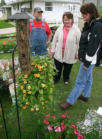 A COLORFUL SALE -- David and Connie Krebsbach of Austin, left,  look over the flowers and plants available at a sale hosted by Lynn Cole of Stewartville, right. Cole's display was a colorful part of Stewartville's citywide garage sale. 