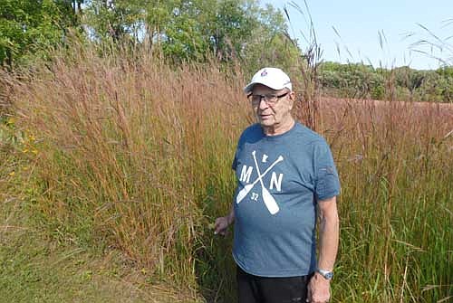 Don "Buck" Amos stands amid the bluestem grasses at Sunset Prairie Park in west Stewartville.