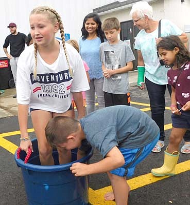 Rylee Lilly, 10, of Stewartville, a fifth grader at Bear Cave Intermediate School, left, nears the end of her one minute of grape stomping as partner Vincent Prazak, 7, of Pine Island, stirs the grapes.