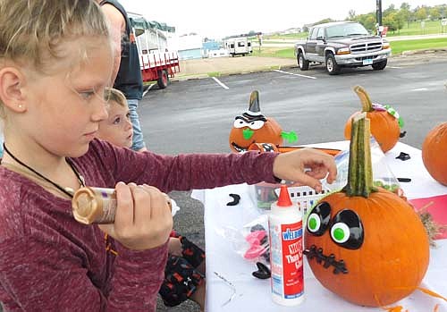 Kayda Suess, 10, a fourth grader at Bear Cave Intermediate School, in the foreground at left, focuses on the task at hand as she decorates a pumpkin during the Stewartville Morning Lions Club's annual Fall Festival on Saturday, Sept. 21.