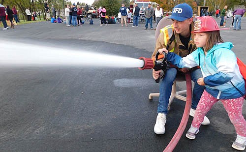 Emerson Porter, 4, of Stewartville, assisted by Stewartville firefighter Jake Petrich, uses a hose at the Stewartville Fire Department's annual open house at the local Fire Station on a mild and breezy Wednesday evening, Oct. 9. Hundreds of children and their parents visited the Fire Station for the event, held to celebrate Fire Prevention Week. Firefighters also helped kids explore fire trucks, offered a Jaws of Life demonstration and answered visitors' questions.