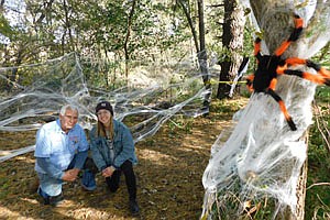 SPOOK CITY WITH THE SPIDER -- Halloween came frighteningly early for the 511  guests who attended the eighth annual Spook City in the Woods in rural Racine Friday and Saturday evenings, Oct. 18 and 19. Guests walked a sectioned-off path decorated with skeletons, witches, spiders and more. Above, Roger Nelson of Nelson Electric, LLC, the sponsor of the event, and Jade Schmeling, one of the original organizers, pose with a large spider and a tangle of cobwebs. The event has been held every year since 2012 to raise money for PACER, a bullying prevention organization. For more details, see the story at left.