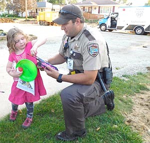 Arianna McCrossen, 4, of Stewartville, accepts a variety of gifts from Mike Strelow, Stewartville's COPS deputy, during a National Night Out celebration on Aug. 6.