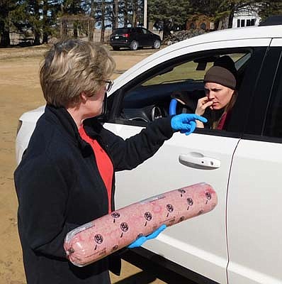 Tracy Hoover, a member of Racine United Methodist Church, left, prepares to give away a package of hamburger donated by 2 Brothers BBQ of Stewartville to a resident who pulled up to the church's parking lot on Tuesday afternoon, March 31.