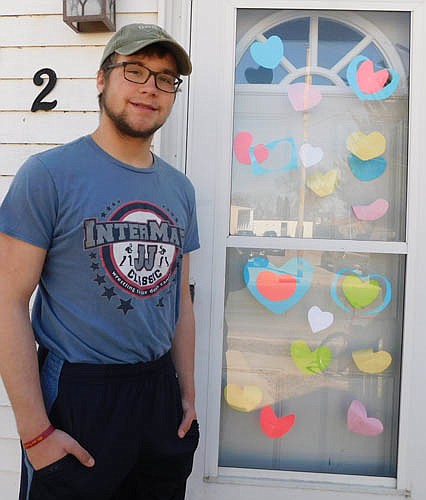 Christian Sackett stands near his front door, covered with hearts of many colors.