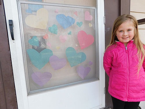 Aly Cox, 7, worked with her mother, Cali Miller, to place red, blue and purple hearts on the door of her Stewartville home.