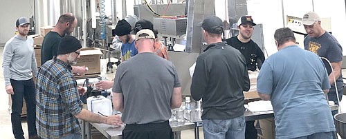 Here, workers from The Coffee Club at Jimmy's Salad Dressings & Dips form an assembly line to bottle hand sanitizer from Harmony Spirits, a craft distillery from Harmony, Minn.