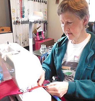 Julie Hayes sews a piece of cloth that will soon be transformed into a coronavirus mask.