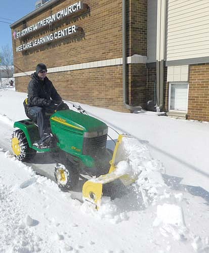 Travis Morse of Stewartville clears snow from the sidewalk near St. John's Lutheran Church and the Wee Care Learning Center on Monday morning, April 13 after a spring storm dumped about 7.5 inches of snow on Stewartville and the area on Easter Sunday, April 12.