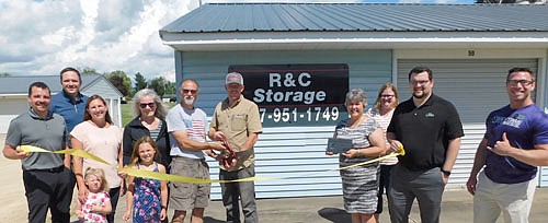 Al Chihak and Mike Ryan, at center-left with the scissors, with their wives, Peggy Chihak and Jenny Ryan, fourth and third from left, respectively, cut the ribbon to ceremoniously open R&C Storage on Wednesday, June 24. The Chihaks and Ryans bought the business from Clair Mrotek this past January. The Ryans' daughters, Claire, 3, and Kendall, 7, stand near Jenny and Peggy. Stewartville Area Chamber of Commerce members who welcomed the new business owners include, from left, Josh Buckmeier of ONB Bank, Nick Johnson of Thrivent Financial, Myrna Welter, Chamber membership coordinator; Gwen Ravenhorst, Chamber administrator; Dylan Smallwood of First Farmers&Merchants Bank; and Jared Johnson of Anytime Fitness. R&C Storage offers 89 storage units in Stewartville and 31 in Racine.