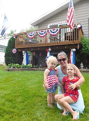 Many Stewartvile residents celebrated the Fourth of July by taking part in the Stewartville Area Chamber of Commerce's Ultimate Patriotic Yard Challenge, decorating their homes in red, white and blue. Above, Julie Ristau, who lives at the 500 block of Sixth Street Northeast, holds her daughter Aubrie, 4, right, and neighbor Charlotte Doll, 21 months, as the three pose in front of the Ristau's finely decorated home.