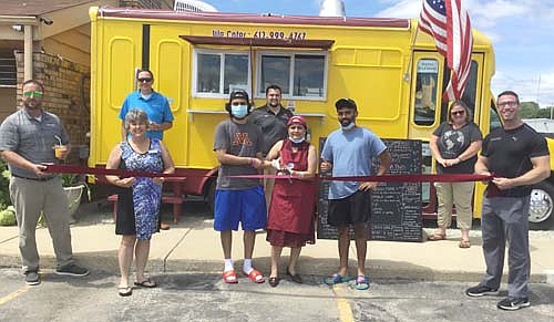 Members of the Stewartville Area Chamber of Commerce welcomed Beyond Foods-Vegan Food Truck to the local business community with a ribbon-cutting ceremony on Wednesday, July 22. The business, open near America's Stay Inn on Wednesdays through Sundays from 5 p.m. to 9 p.m. each day, offers fresh vegan and vegetarian food options. Nila Patel of Beyond Food-Vegan Food Truck, standing in the center with the scissors, cut the ribbon to officially open the business as her sons, Vandan Patel, third from left in front, and Hari Patel, second from right in front, assist their mother. Other Chamber members who attended the ceremony include, front row, from left, Mike Rainey of Bremer Bank, Myrna Welter, Chamber membership coordinator; and Jared Johnson of Anytime Fitness. In back, from left, are Nick Johnson of Thrivent Financial, Dylan Smallwood of Elcor Realty, and Gwen Ravenhorst, Chamber administrator.
