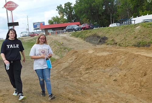 A PATH IN PROGRESS -- Elena Bremen, left, and Abbi Parry, sophomores-to be at Stewartville High School, walk  near the base of a path that will run from Dairy Queen downhill to a nearby bike trail. Bill Schimmel Jr., city administrator, said residents like the idea of connecting DQ to the bike trail. "We've already gotten some good comments," he said.