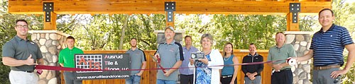 The Stewartville Area Chamber of Commerce welcomed Ausrud Tile &&#8200;Stone to the local business community with a ribbon-cutting ceremony at the newly built amphitheater at Bear Cave Park on Wednesday, Sept. 2. Chris Ausrud, holdng the scissors, and Taylor Ausrud, holding the banner at right, were on hand for the ceremony, along with Chamber members, from left, Jared Johnson of Anytime Fitness; Adam Gehling of Country Financial; Ed Kruger of EZ Camper Rental; Myrna Welter, Chamber membership coordinator; Megan Romens of Mary Kay; Josh Buckmeier of ONB&#8200;Bank; Bill Schimmel Jr., city administrator; and Nick Johnson of Thrivent Financial, Chamber president.