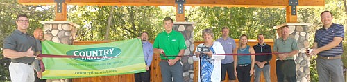 The Stewartville Area Chamber of Commerce welcomed Country Financial to the local business community with an official ribbon-cutting ceremony at the newly constructed amphitheater at Bear Cave Park on Wednesday, Sept. 2. Adam Gehling, holding the scissors in the front row, along with Ryan Plattenberger and Allan Johnson, holding the banner, all of Country Financial, were on hand for the ceremony, along with Chamber members, from left, Jared Johnson of Anytime Fitness; Myrna Welter, Chamber membership coordinator; Ed Kruger of EZ Camper Rental; Megan Romens of Mary Kay; Josh Buckmeier of ONB Bank; Bill Schimmel Jr., city administrator; and Nick Johnson of Thrivent Financial, Chamber president.