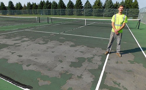 Jake Chopp, a maintenance II&#8200;employee for the city of Stewartville's public works department, stands at one of four time-worn Bear Cave Park tennis courts scheduled to be resurfaced next spring.