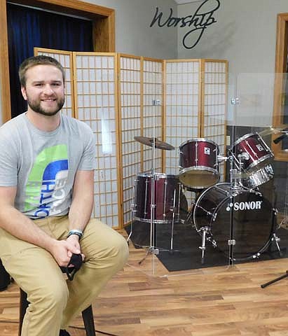 Aaron Regnier , the new associate pastor of student ministries at Grace Evangelical Free Church, poses near the drum set used at Grace Church's Sunday services.