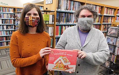 Sarah Schramek, an aide at the Stewartville Public Library, left, and Nate Deprey, library director, display one of the 120  Build Your Own Gingerbread House kits Deprey purchased from Five Below in Rochester. Beginning Monday, Dec. 7, local and area residents may take home a free, already-constructed house.