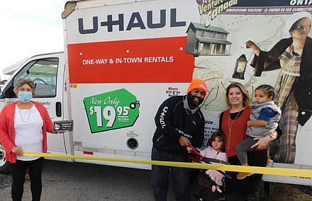 J.C. Rodriguez, owner of Stewartville's new U-Haul store, joined by his wife, Larissa, and children Daniella, 4, standing, and Aries, 2, cuts the ribbon to officially open the new Main Street business. Myrna Welter, membership coordinator of the Stewartville Area Chamber of Commerce, welcomes the Rodriguez family to the local business community. The business is located across the street from the downtown Kwik Trip