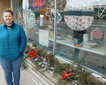 Jen Schurmeier stands near the front window at C&M Screen Printing, which she decorated with bulbs made of fabric hoops, snowflakes made of hangers, and more. She thanked the owners of the  businesses who welcomed her designs. "These businesses were kind enough to lend me their windows, so I could do my thing and spread a little extra joy," she said.