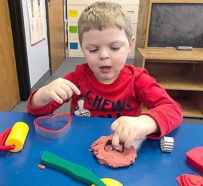 Children at St. John's Wee Care Learning Center celebrated Valentine's Day a few days early last week, working on heart-shaped projects on Wednesday, Feb. 10. Conor Hanson, 4, focuses on making valentine shapes in his own black cherry-scented dough. 