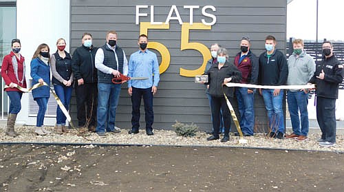 Jeremy Kane, construction manager for Schoeppner Construction of Rochester, holding the ceremonial scissors, cut the ribbon as the Stewartville Area Chamber of Commerce welcomed Flats 55, a 55-unit, 73,000 square foot apartment complex, to the local business community on Friday, March 5. Others who attended the ceremony include, from left, Chamber members Rhonda Fuhrer of HMR Interiors, Megan Romens of Mary Kay Cosmetics and Melissa Sue Leuning of Premium Support, LLC; Bryan Schoeppner, contractor; (Kane, with the scissors), Darren Groteboer, a partner with PGGM1, LLC, the developer for the project; Mayor Jimmie-John King, Myrna Welter, Chamber membership coordinator; Stewartville City Councilperson Craig Anderson; Chamber member Adam Gehling of Country Financial, Dylan Carty, a licensed real estate broker and owner of Realty Growth of Rochester, and Chamber member Jared Johnson of Anytime Fitness.