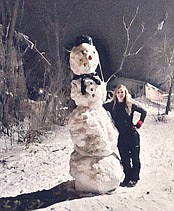 Brooke Carr poses with the 9-foot snowman she and friend Alexander Blake made last week. Carr and Blake used snow from the nearly eight inches of white powder that fell on Stewartville and the area on Monday, March 15. They worked for about two hours to build the snowman, which stood along the east side of Main Street for two days. On Wednesday, March 17, someone removed about half of its body.
