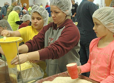 Jacqui Rinn of Stewartville holds a plastic bag under a funnel as her daughter Riley, left, adds an ingredient and daughter Reese waits to add another during the 15th annual Food for Kidz food-packaging event for the poor at the Stewartville Civic Center on Saturday, April 7, 2018. The Stewartville Kiwanis Club's Food for Kidz, traditionally held the first week of April, has been postponed by the COVID-19 pandemic until Saturday, Oct. 23.