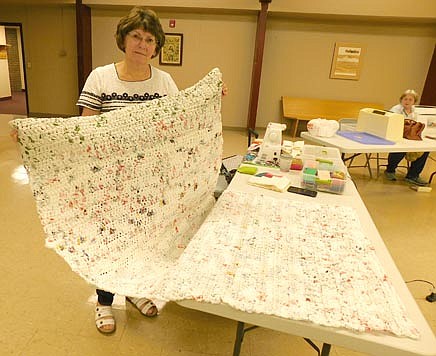 Kathy Ottjes, a member of Zion Lutheran Church, has joined three couples from two different Stewartville churches to crochet plastic bags into outdoor mats for the homeless. Jo Olson, another crocheter, is in the background.