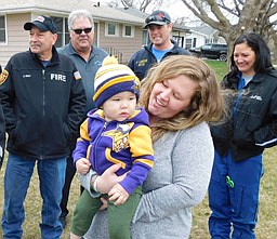 Logan Olson, 18 months old, resting comfortably in the arms of his delighted mother, Erin, returned to his Stewartville home along Third Avenue Northeast safe and sound on April 19. After falling into a retention pond on April 7, Logan was rescued by his dad, Darwin (DJ), his babysitter, and several passersby who helped administer CPR. Stewartville first responders, the Mayo Clinic Ambulance Service and Olmsted County deputies also responded, with the first responders taking over the rescue efforts. Logan, taken to St. Marys Hospital in critical condition, remained hospitalized for nearly two weeks before returning home last week. Stewartville first responders who welcomed him home include, from left, Steve Wolf, Greg House, Justin Lonien and Lisa Jelinek.