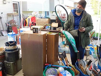 Tracy Zeimet of Bloomington looks closely at a tennis racket as she browses among the items at the home of Wes Alrick, 700 Sixth Street Northeast, during the Stewartville Citywide Garage Sale on Thursday, May 6. "I come here to shop," Zeimet said. "It's my favorite time of the year."