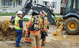 Mark Herman of Minnesota Energy, left, speaks with two firefighters from the Stewartville Fire Department shortly after a natural gas line ruptured at the 100 block of Third Street Northwest on Monday morning, May 3. Captain Steve Denny of the SFD said the gas line broke after an NPL Construction Co. employee, digging to gain access to the line, hit it with a backhoe.