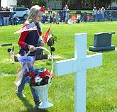 Hannah Meyerhofer, poppy princess, carries flowers to a gravesite at Woodlawn Cemetery during Stewartville's annual Memorial Day ceremony.