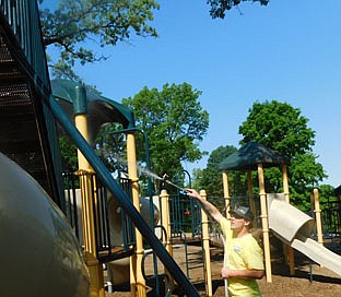 Andrew Frank, a technician for Presto SoftWash, cleans the city of Stewartville's playground equipment at Stewartville's Florence Park on Tuesday morning, June 8. As a way to give back to the community, the company did the work at no charge.