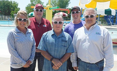 First Farmers&Merchants Bank has donated 1,000 sunglasses to swimmers at the Stewartville pool, Tiger Time students and pool staff. Modeling the sunglasses are, front row, from left, above, Dana Stier, who works in lender analysis for First Farmers, Mayor Jimmie-John King, and Dave Feddersen, president of First Farmers. Back row, from left, Bill Schimmel Jr., city administrator; and Jake Flynn, Stewartville pool manager. Below, at left, Mayor King, Stier and Feddersen distribute the sunglasses to residents lined up to swim at the pool.