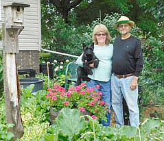 Larry and Joyce Shatek, posing with their Scottish terrier, Bonnie, stand among the many flowers and plants at their front lawn along Third Avenue Southeast. The Shateks spend a total of three to four hours a day weeding and watering their flower and plant garden in their front yard and in their vegetable and produce garden in their back yard.  "We're both retired," Joyce said. "This is our hobby. We're both from the farm, so we like gardens."