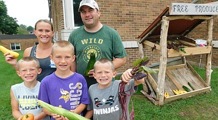 Amanda and Jamie Meyer, in back, and their children, in front, from left, Lucas, James and Dylan, hold samples of the produce the members of St. John's Lutheran Church have grown in the church garden on the church's property in Stewartville. Jamie built the stand at right, where the free produce has been on display since mid-June and will remain available as this summer's harvest continues.