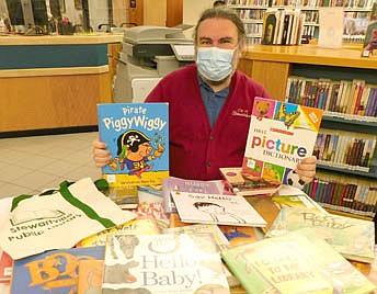 Nate Deprey, director of the Stewartville Public Library, displays a small collection of the thousands of kids books, picture books, juvenile fiction, early readers books and young adult novels that will go on sale at the Library this Wednesday, Aug. 18 from 10 a.m. to 5 p.m. and Thursday, Aug. 19 from 10 a.m. to 3 p.m. On Thursday from 3 p.m. to 7 p.m., shoppers will pay $5 each for a tote bag (pictured at far left on the table) full of any books left over.